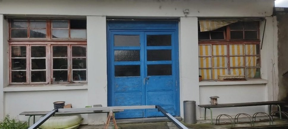 Avant : façade d'atelier avec anciennes fenêtres en bois et porte bleue