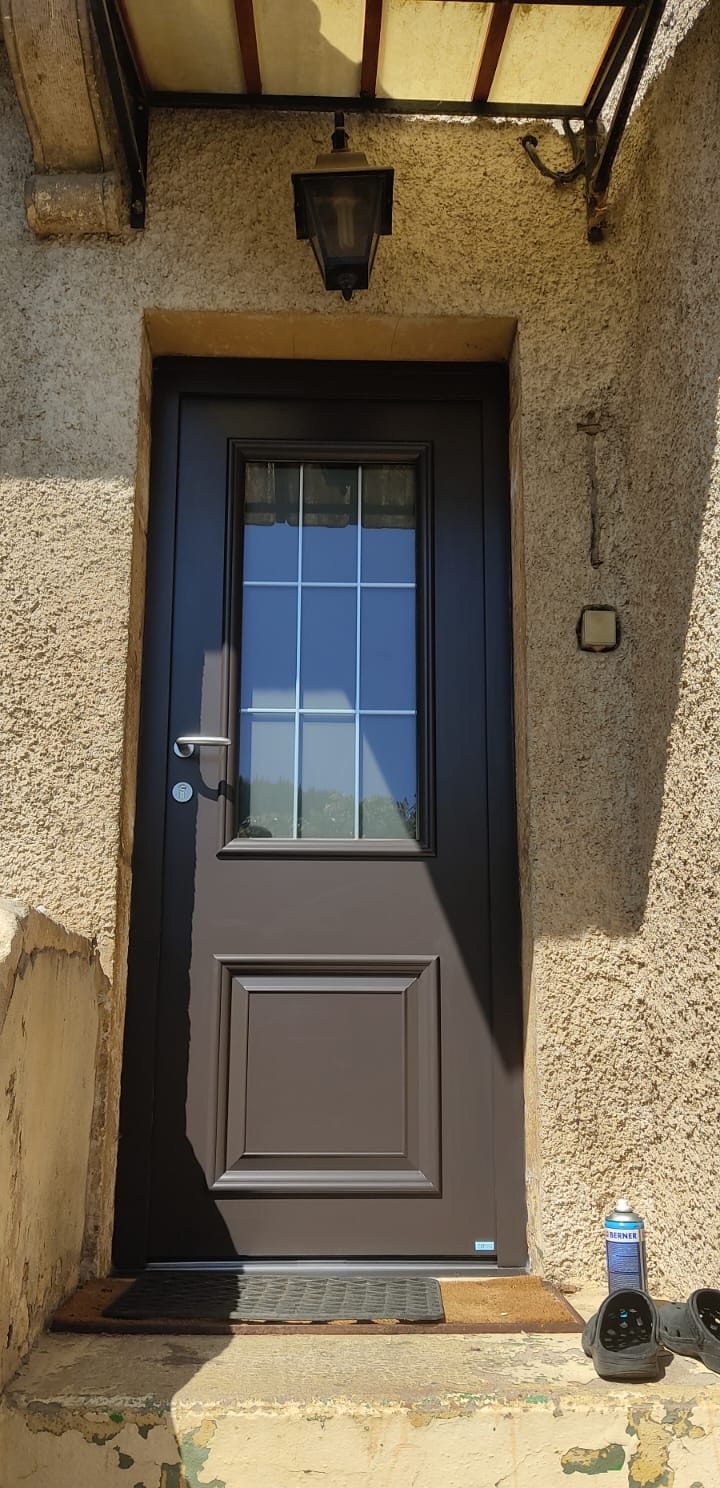 Porte d'entrée brune vitrée sous un porche