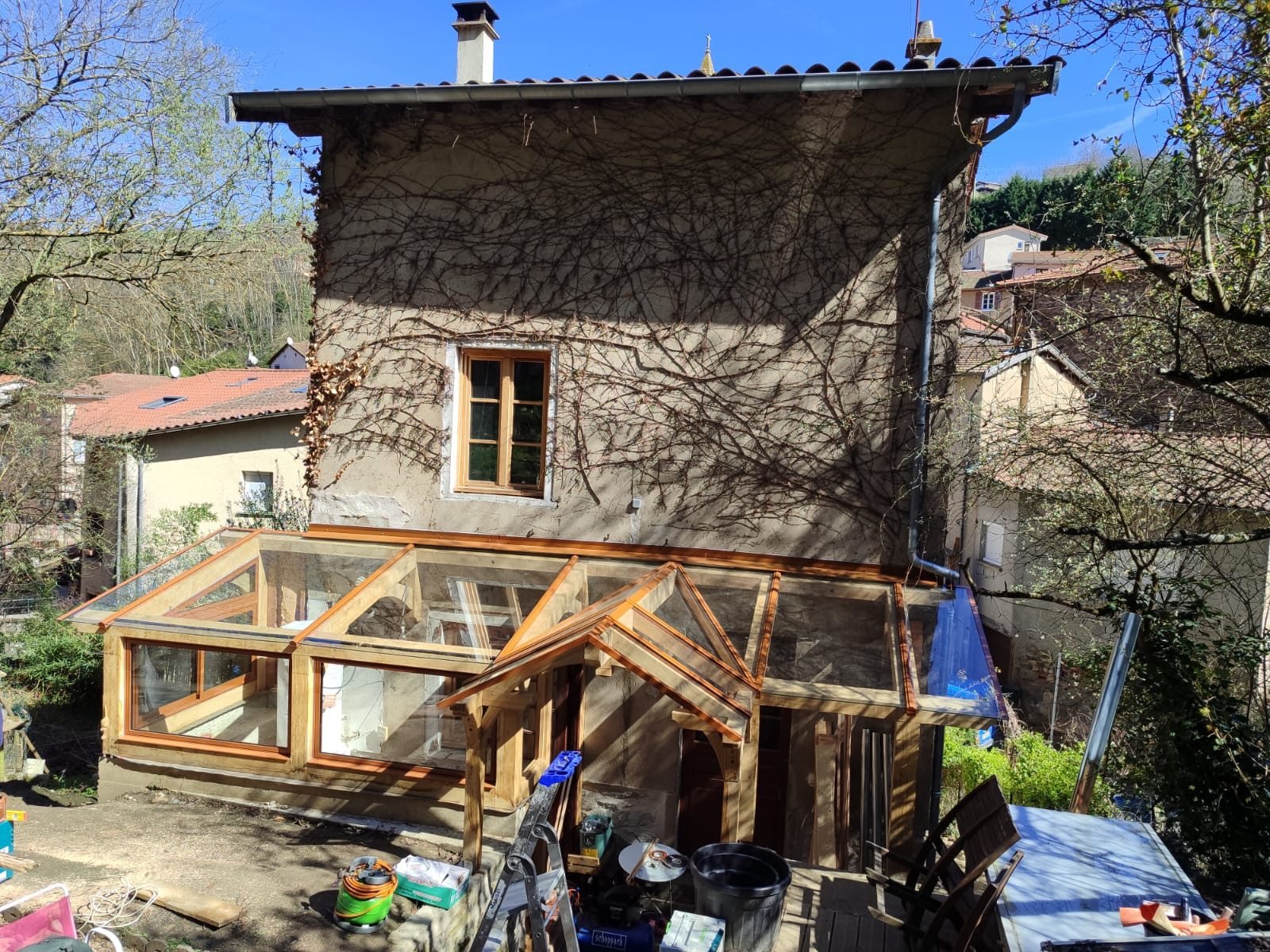 Sas d'entrée vitré à ossature bois construit par La Fourmi contre une maison en pierre