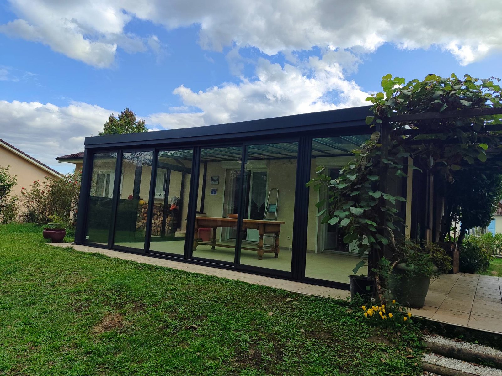Véranda vitrée à cadre anthracite dans un jardin